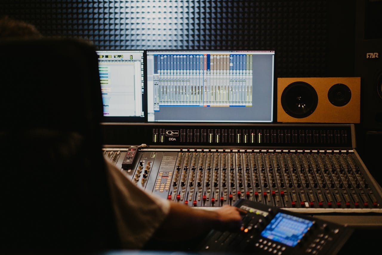 Close-up of a professional audio mixing console with sound engineer in a recording studio.